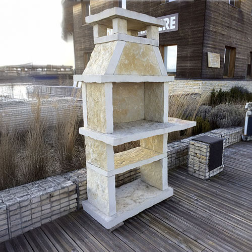 Barbecue en pierre artisanal installé dans un jardin, avec plan de travail en pierre.