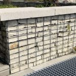 Couvertine bouchardée en pierre posée sur un banc en gabions dans un aménagement extérieur.