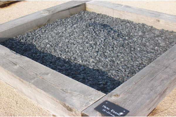 Pierres décoratives en pierre naturelle posées dans un massif de jardin, utilisées pour la décoration et les bordures.