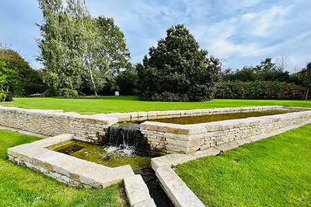 couverture de mur en pierre naturelle devant une fontaine dans un jardin